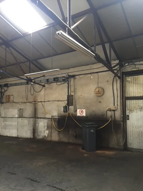 Murs bruts et charpente métallique du hangar avant transformation